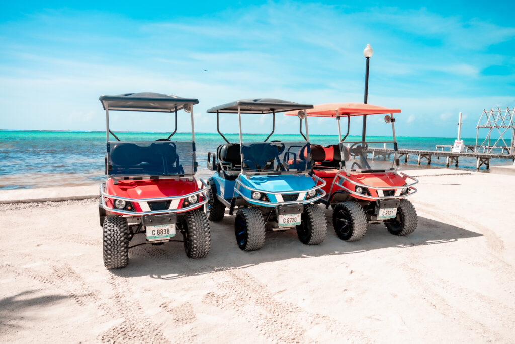 a group of golf carts on a beach in san pedro belize